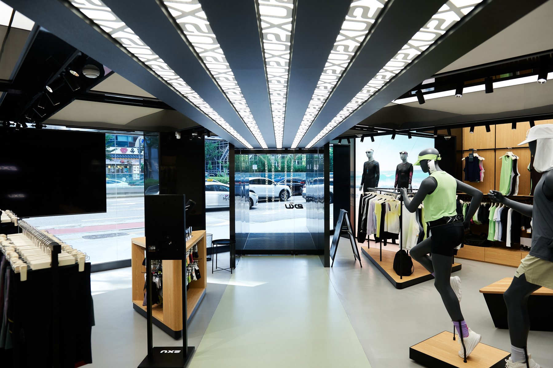 2XU 서울 플래그십 스토어 매장. 천장을 가로지르는 빛의 리브가 쇼윈도 쪽으로 이어진다
